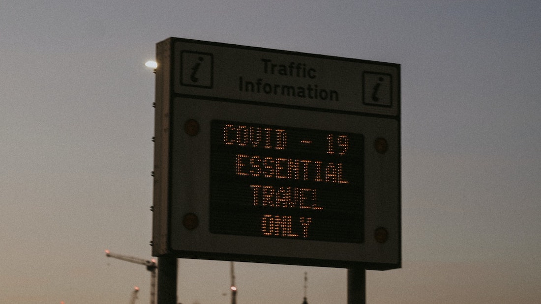 A hoarding that says "COVID-19 Essential Travel Only"